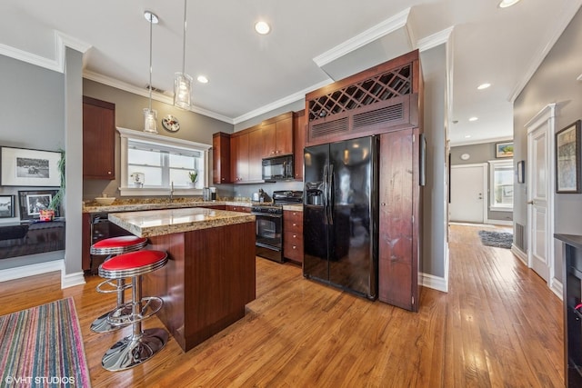 2451 S Western Ave Unit 3N, Chicago, IL 60608 - kitchen featuring black appliances, light wood-style flooring, hanging light fixtures, a center island, and a kitchen breakfast bar