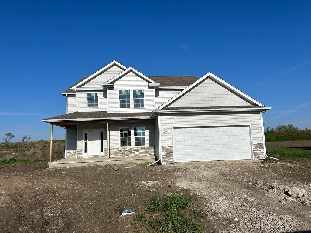 1415 Warwick, Savoy, IL 61874 - view of front of property featuring stone siding, a garage, covered porch, and dirt driveway
