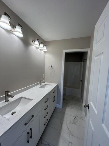 1415 Warwick, Savoy, IL 61874 - bathroom with marble look tiles, double vanity, and a shower