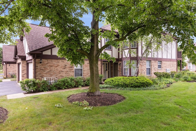 283 E Fabish Dr, Buffalo Grove, IL 60089 - tudor-style house with a front lawn, brick siding, a garage, and a shingled roof
