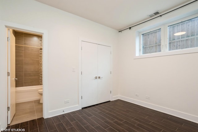 unfurnished bedroom featuring baseboards, dark wood-type flooring, and a closet