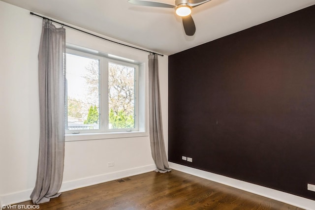 spare room featuring a ceiling fan, baseboards, and dark wood-style flooring