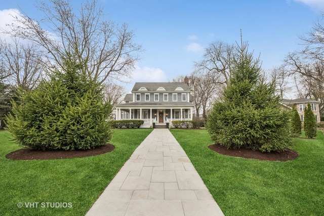 view of front of property with a chimney, a porch, and a front lawn