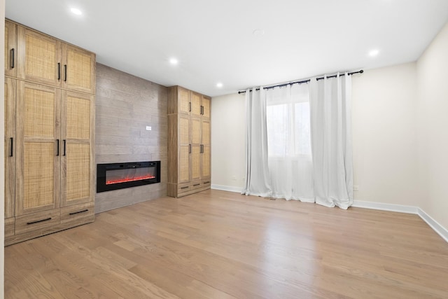 unfurnished living room with a large fireplace, baseboards, light wood-style floors, and recessed lighting