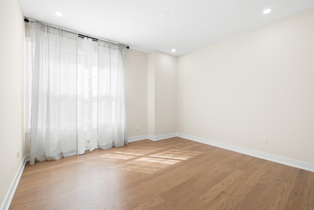 unfurnished room with wood finished floors, baseboards, and recessed lighting