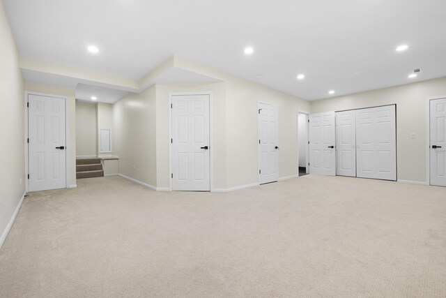 basement featuring light colored carpet, baseboards, recessed lighting, and stairs