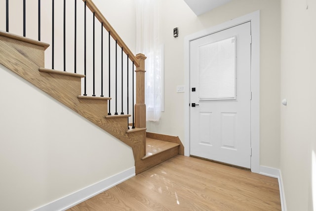 foyer entrance with wood finished floors, stairway, and baseboards