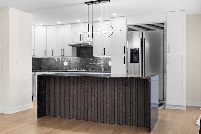 kitchen with appliances with stainless steel finishes, under cabinet range hood, dark countertops, baseboards, and recessed lighting