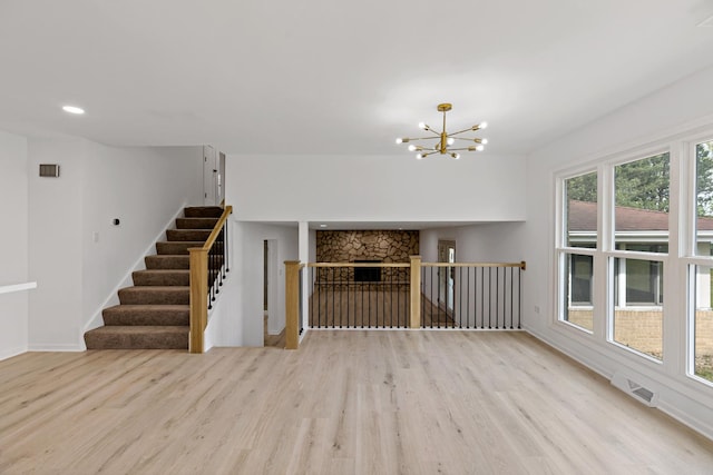 unfurnished living room with wood finished floors, a chandelier, baseboards, stairway, and recessed lighting