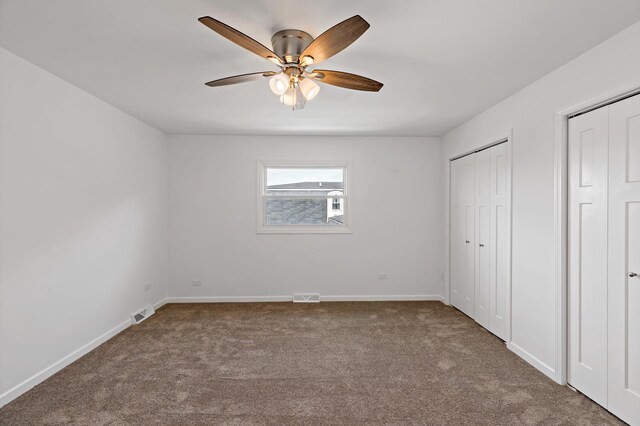 unfurnished bedroom with carpet, baseboards, and multiple closets