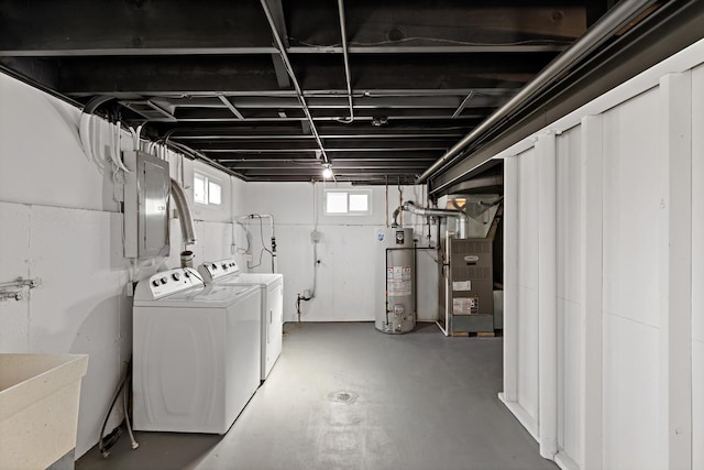 basement featuring gas water heater, independent washer and dryer, heating unit, and a sink