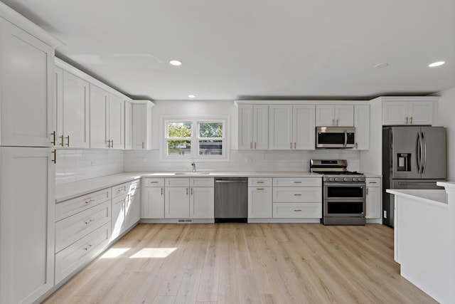 kitchen featuring stainless steel appliances, light wood finished floors, backsplash, light countertops, and recessed lighting
