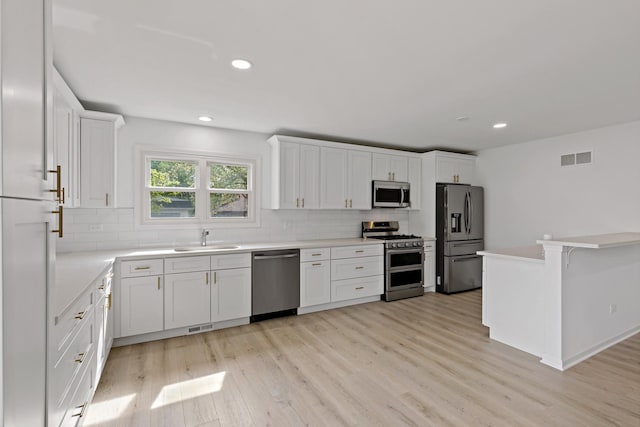 kitchen featuring stainless steel appliances, a sink, tasteful backsplash, white cabinetry, and recessed lighting
