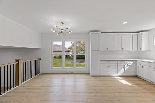 unfurnished dining area with light wood-style floors, a chandelier, and recessed lighting
