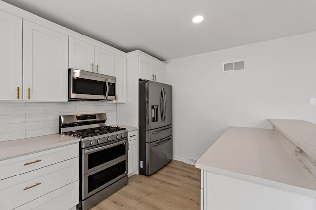 kitchen featuring stainless steel appliances, backsplash, light wood finished floors, white cabinetry, and light countertops