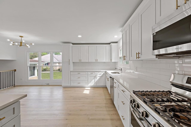 kitchen featuring appliances with stainless steel finishes, recessed lighting, light wood-style flooring, light countertops, and backsplash