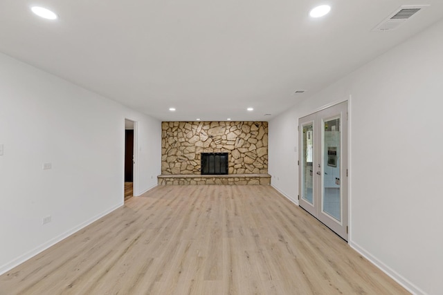unfurnished living room featuring light wood finished floors, recessed lighting, baseboards, and a stone fireplace