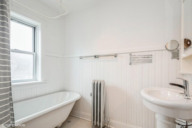 1225 W Jarvis Ave Unit 3, Chicago, IL 60626 - full bathroom featuring radiator heating unit, a soaking tub, a wainscoted wall, healthy amount of natural light, and a sink