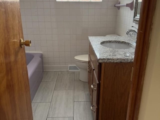 772 Memorial Dr, Calumet City, IL 60409 - bathroom featuring vanity, toilet, tile walls, tile patterned floors, and a tub to relax in