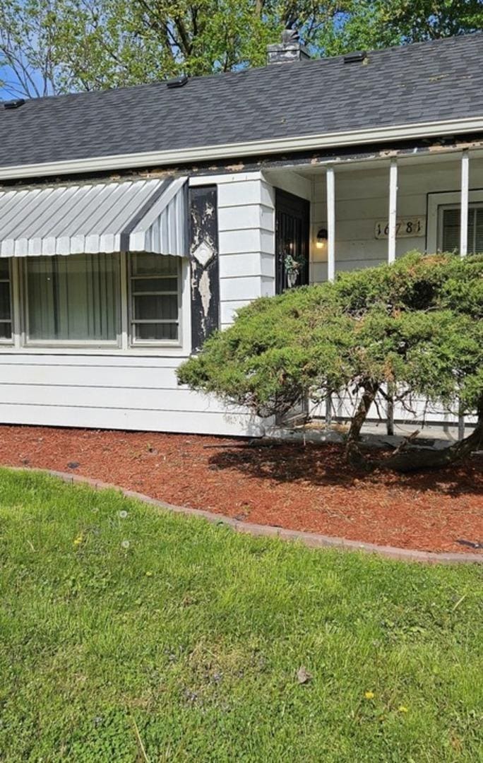 view of home's exterior with a yard and a shingled roof