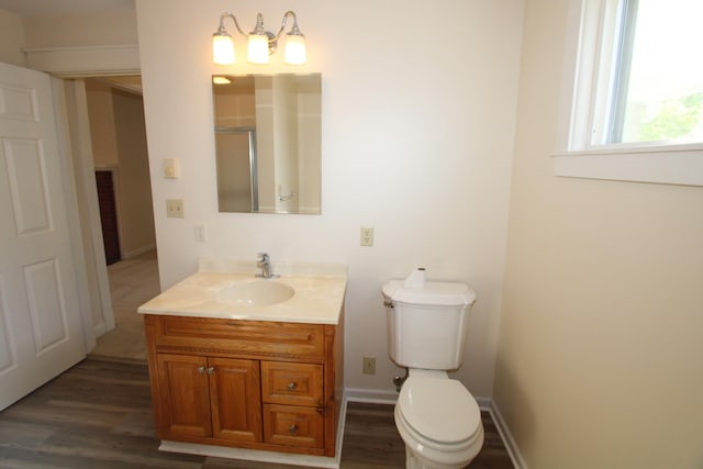 bathroom with vanity, wood finished floors, toilet, and a shower with door