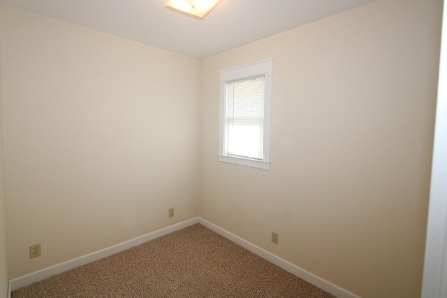 carpeted empty room featuring baseboards