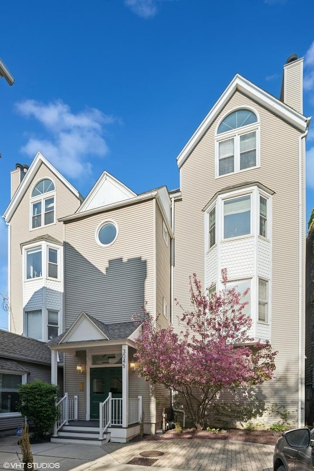 view of front of home featuring a chimney and covered porch