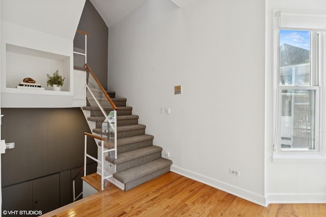 stairway with wood finished floors and baseboards