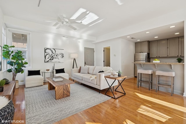 living room with light wood-style floors, ceiling fan, recessed lighting, and baseboards