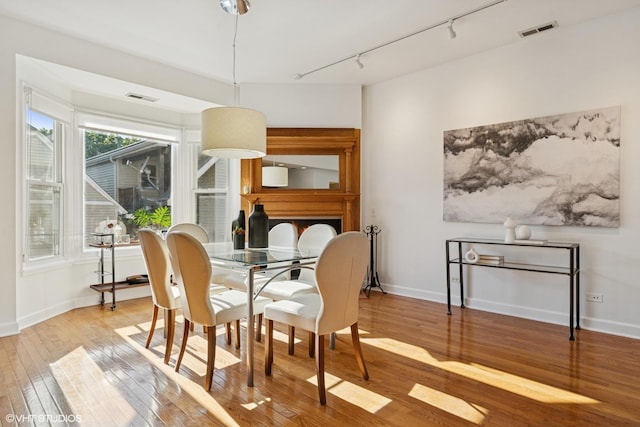 dining space featuring hardwood / wood-style floors, rail lighting, and baseboards