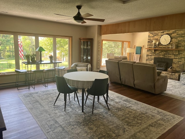 2493 W Mud Creek Rd, Mount Morris, IL 61054 - dining space featuring ceiling fan, a wood stove, healthy amount of natural light, wood finished floors, and a textured ceiling