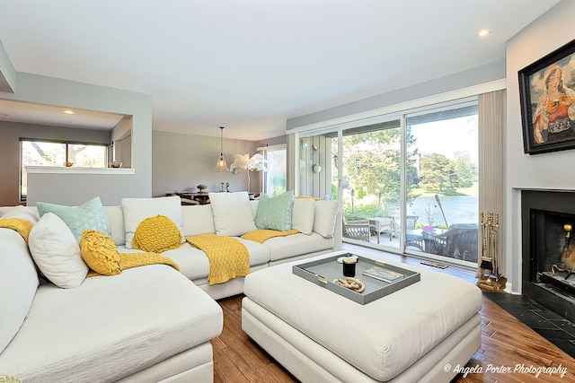living room with plenty of natural light, wood finished floors, a fireplace with flush hearth, and recessed lighting