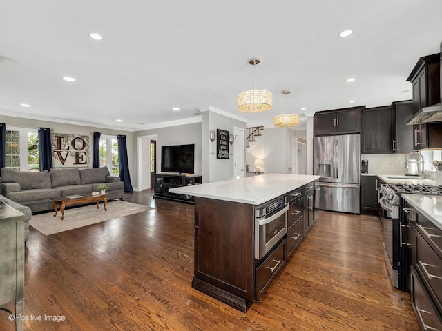 kitchen with stainless steel appliances, a sink, light countertops, ornamental molding, and dark brown cabinetry