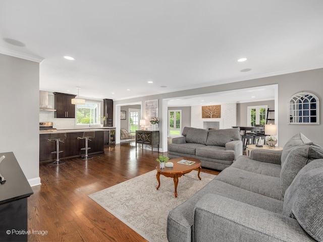 living room featuring ornamental molding, dark wood-type flooring, recessed lighting, and baseboards