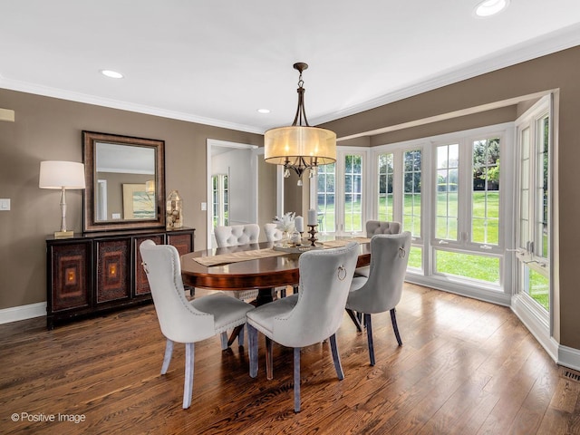 dining space featuring healthy amount of natural light, ornamental molding, a chandelier, wood finished floors, and baseboards