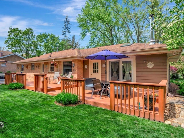 back of house with a wooden deck, a yard, outdoor dining area, and brick siding