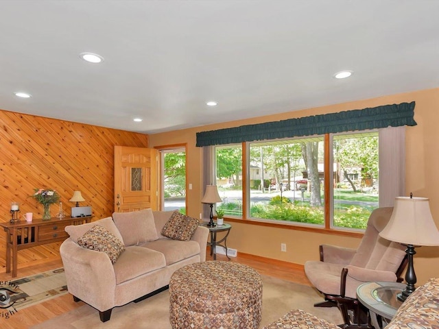 living room featuring recessed lighting, an accent wall, wooden walls, and light wood-style floors