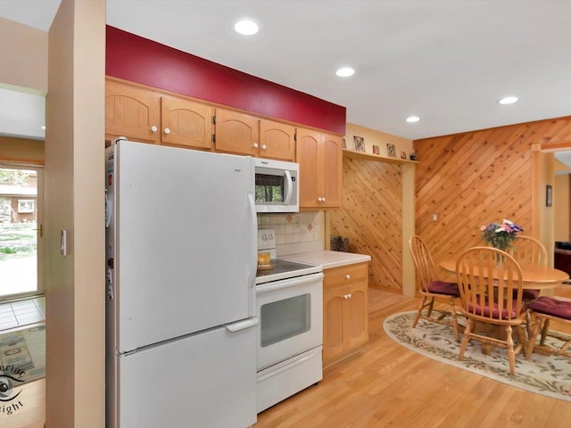 kitchen featuring white appliances, decorative backsplash, light wood finished floors, wooden walls, and light countertops