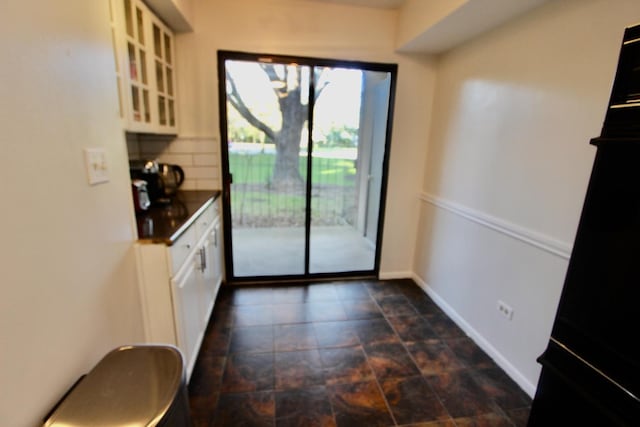 doorway featuring stone finish floors and baseboards