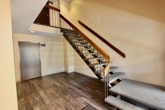 staircase with wood finished floors and a high ceiling
