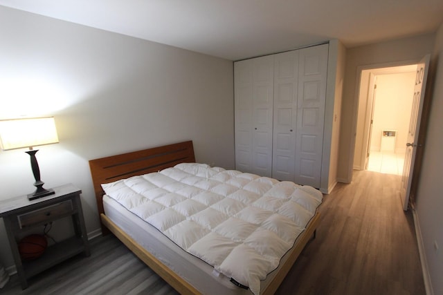 bedroom with light wood-style flooring, a closet, and baseboards