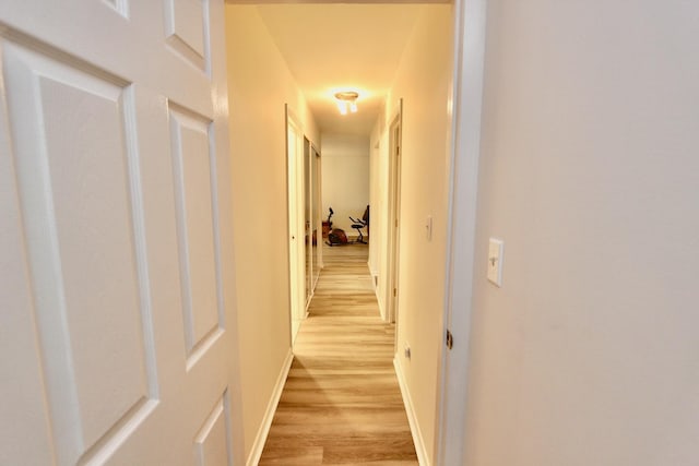 hallway with light wood-style flooring and baseboards