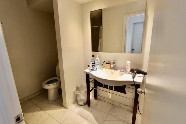 bathroom with marble finish flooring, toilet, vanity, and a shower with curtain