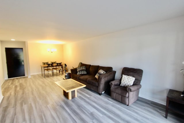 living area featuring wood finished floors, baseboards, and a chandelier