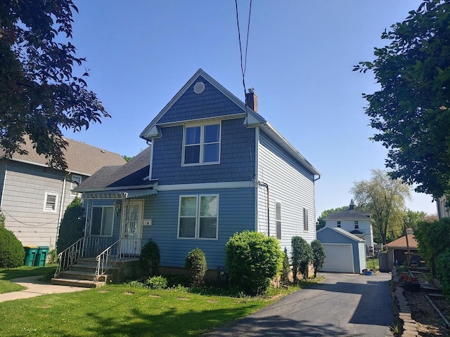 view of front of property featuring a chimney, a detached garage, a front yard, and an outdoor structure