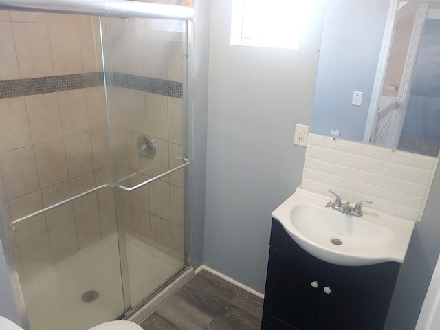 bathroom with wood finished floors, a stall shower, and vanity