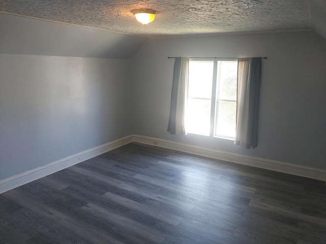 additional living space featuring lofted ceiling, baseboards, dark wood finished floors, and a textured ceiling