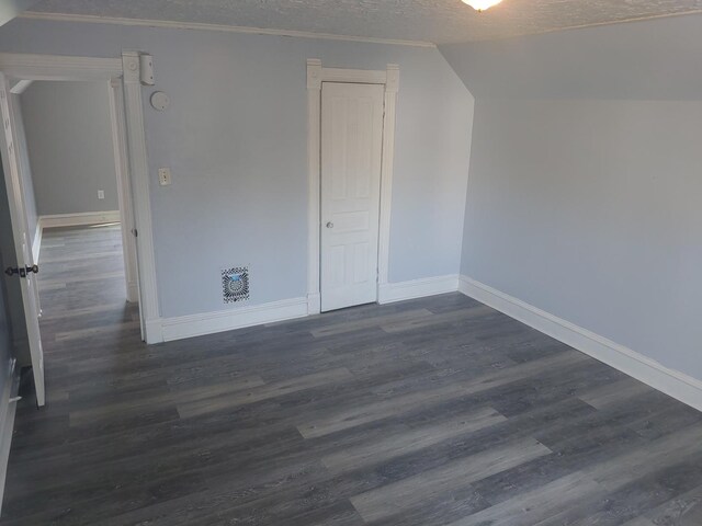 bonus room with baseboards, a textured ceiling, dark wood-type flooring, and lofted ceiling