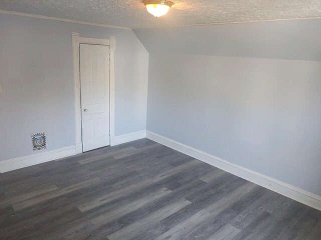 bonus room featuring a textured ceiling, baseboards, dark wood-style flooring, and lofted ceiling