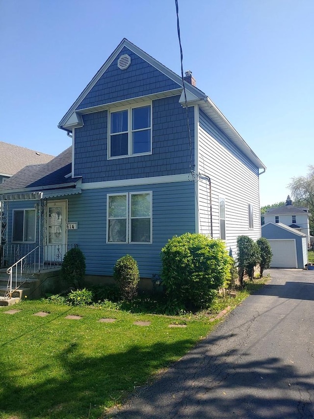 view of front facade with a chimney, a front yard, and a garage
